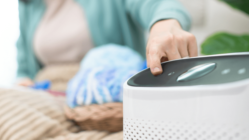 A person sitting on the couch next to a white air purifier