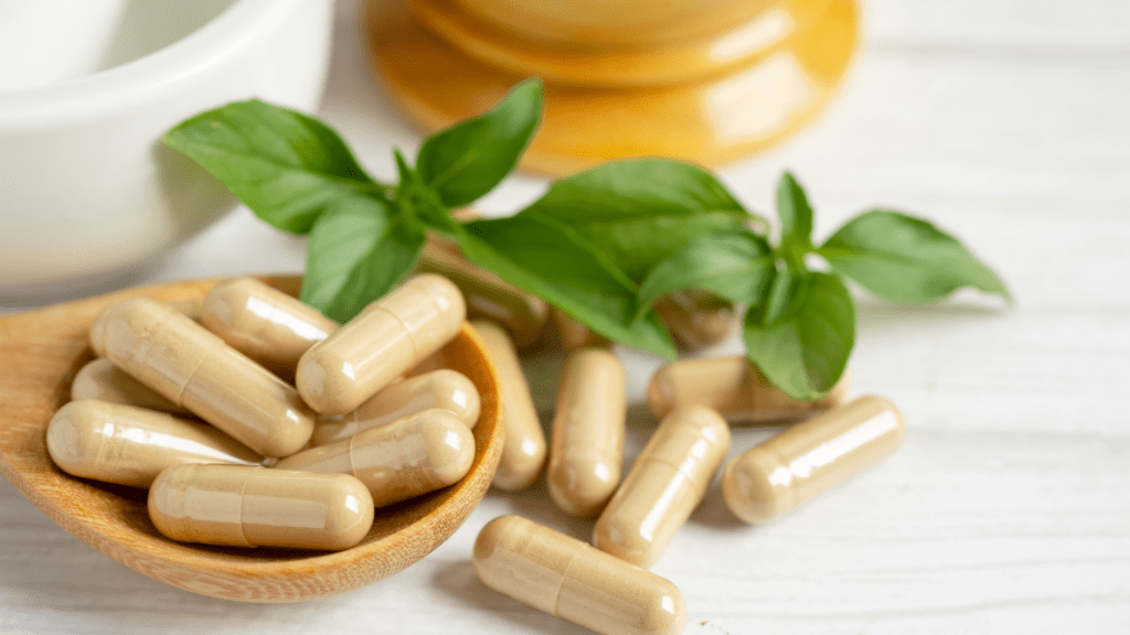 pills on a wooden spoon next to a mortar and pestle