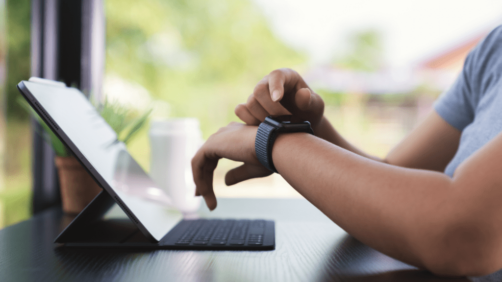 a person sitting at a table with a laptop and a watch on their wrist