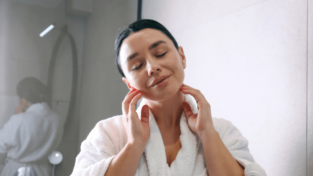 a person in a bathrobe looking at their face in the mirror