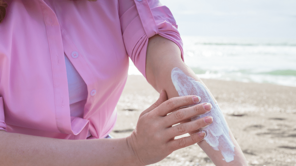 a person is applying sunscreen to their arm on the beach