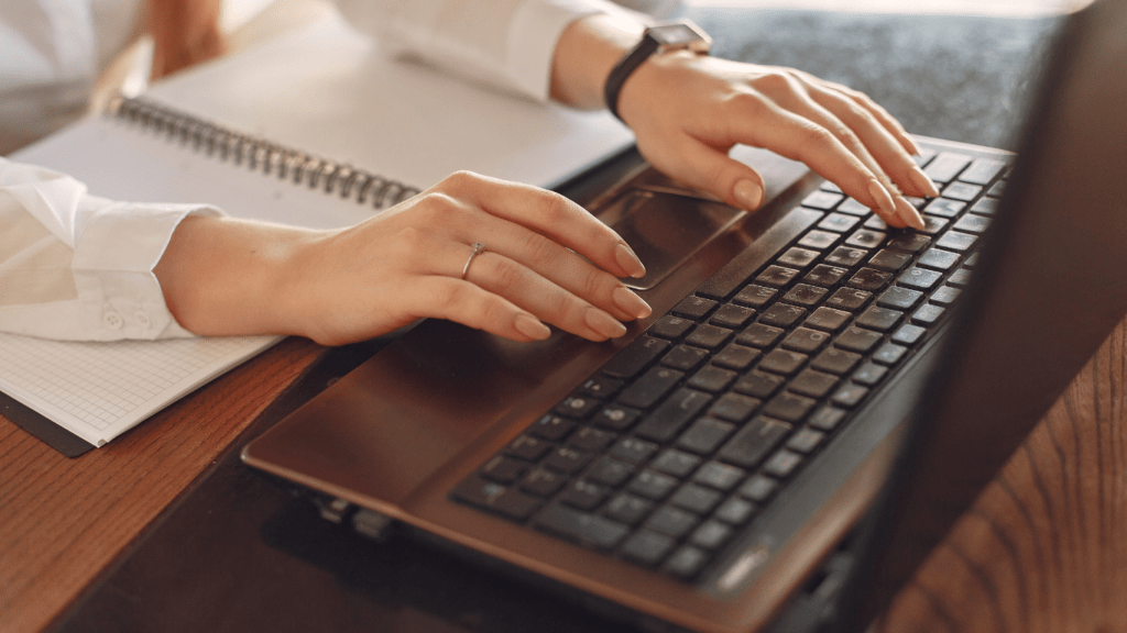 a person sitting at a table with a laptop and a watch on their wrist