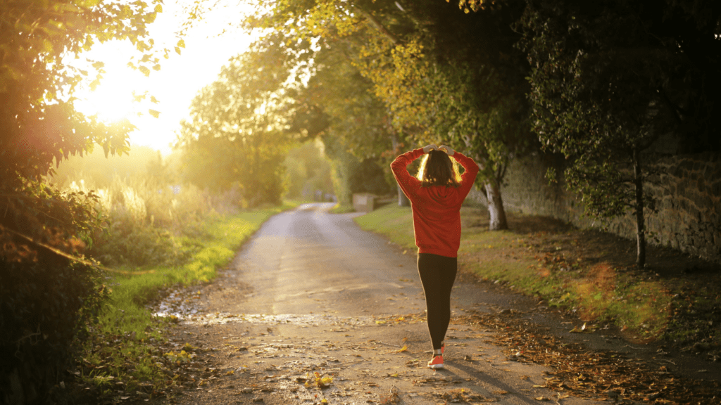 a person walking down the middle of an empty road at sunset