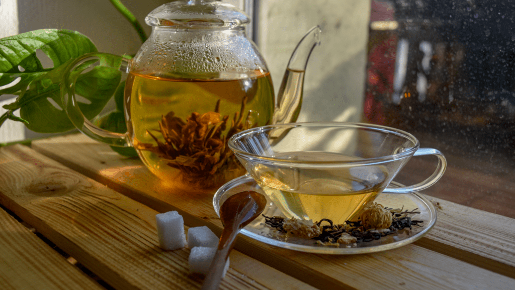 two teapots filled with green tea sitting on a wooden table