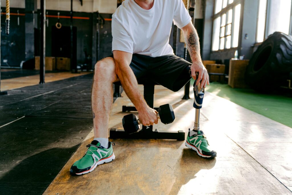 An adult male with a prosthetic leg exercises in a gym, focusing on strength training and fitness.