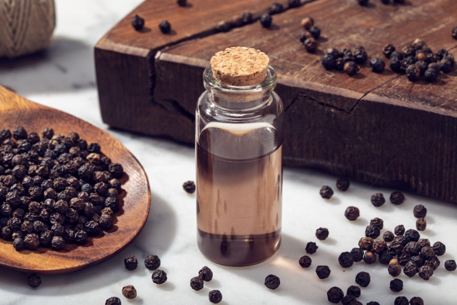 black pepper oil surrounded by peppercorns